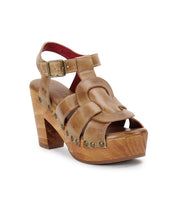 The Caitlin II by Bed Stu is a tan leather platform sandal featuring a wooden block heel, woven leather accents, studded sole detailing, an adjustable ankle strap, and an open toe design.