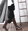 A woman is standing on a ladder in a pair of Bed Stu Della boots.