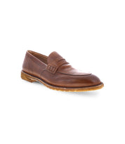 A single brown leather loafer with stitching details and a textured rubber sole, viewed from the front left side. Crafted with Italian elegance by Bed Stu, it features premium leather that exudes sophistication and timeless style under the name Envoy.