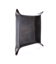A rectangular, black leather Expanse Catchall Tray with snap button corners serves as a perfect catchall tray for keys and loose change. The interior proudly displays the brand "Bed Stu.