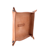 A square, tan leather catchall tray with reinforced corners and metal rivets. The interior features the Bed Stu logo embossed in the center, perfect for holding keys and loose change. Introducing the Expanse Catchall Tray by Bed Stu.