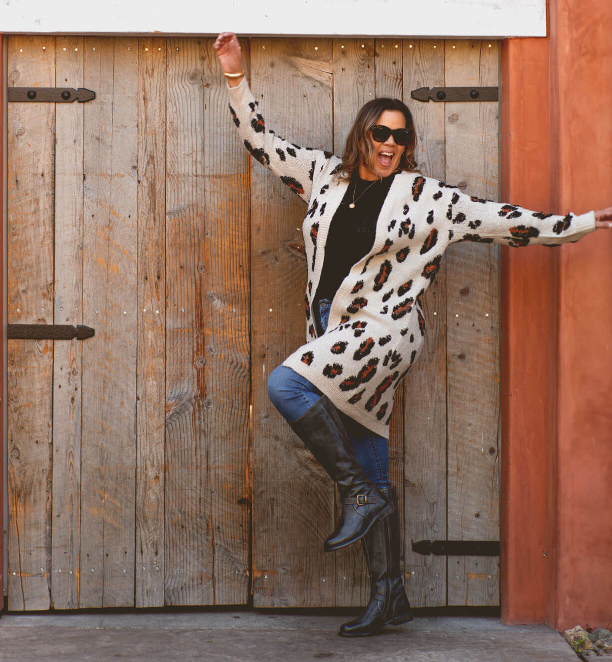A woman wearing a Bed Stu Glaye Wide Calf boots is leaning against a wooden door.