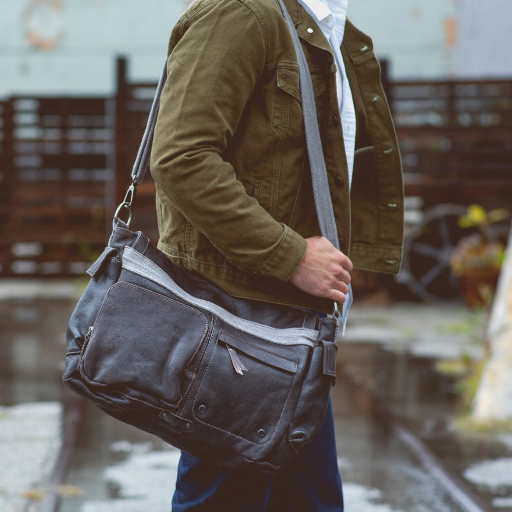 A man carrying a Bed Stu Hawkeye II messenger bag on a street.