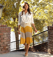 A woman wearing a yellow pleated Hermione skirt and Bed Stu white shirt.