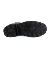 The image showcases the sole of a black Bed Stu Infamy boot with textured patterns, crosses, and grooves designed for traction. This platform boot features a chunky outsole that complements its sleek design.