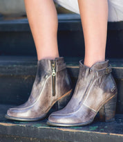 A woman wearing a pair of Bed Stu Isla grey leather ankle boots.