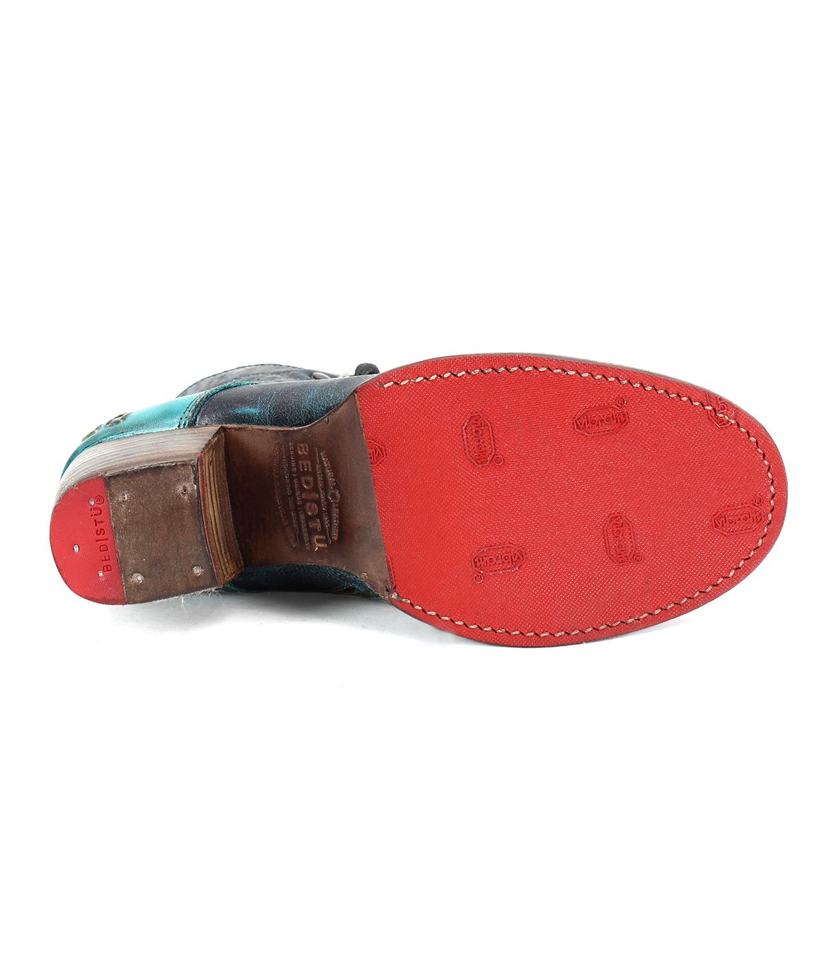The image shows the sole of a Bed Stu Judgement boot, predominantly red with some wear marks and embossed with the branding. The heel is a comfortable block heel made of brown wood, showcasing its iconic design.