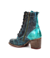 The Judgement by Bed Stu is a high-heeled leather boot featuring blue and turquoise tones, a lace-up front, side zipper, and a comfortable block heel. This iconic design effortlessly combines style and practicality.