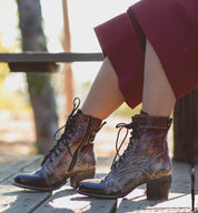 A woman wearing Bed Stu lace up boots on a wooden bench.