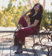 A woman sitting on a Bed Stu wooden bench.