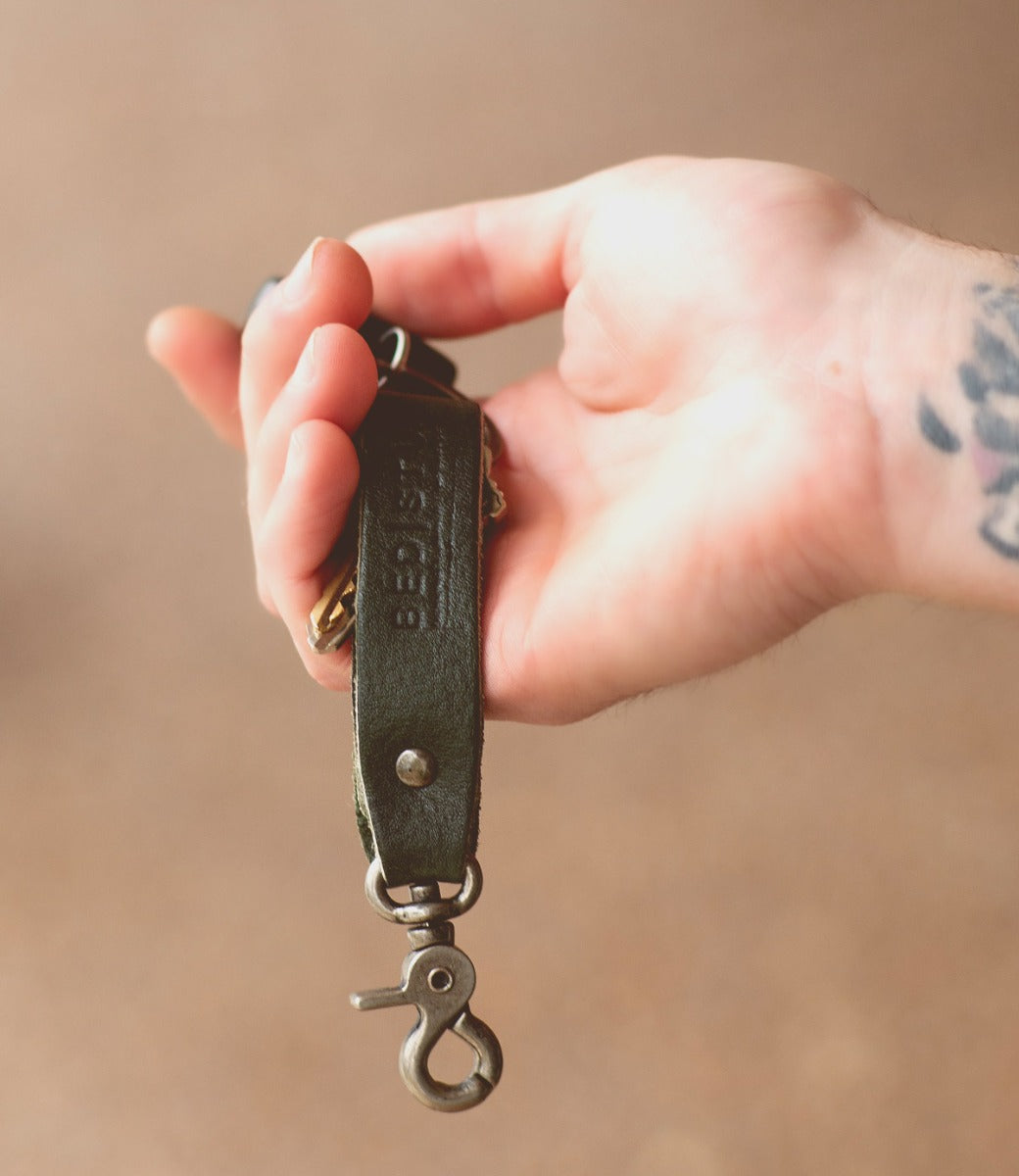 A person holding a Keygrab leather key ring with a tattoo on it from the Bed Stu brand.