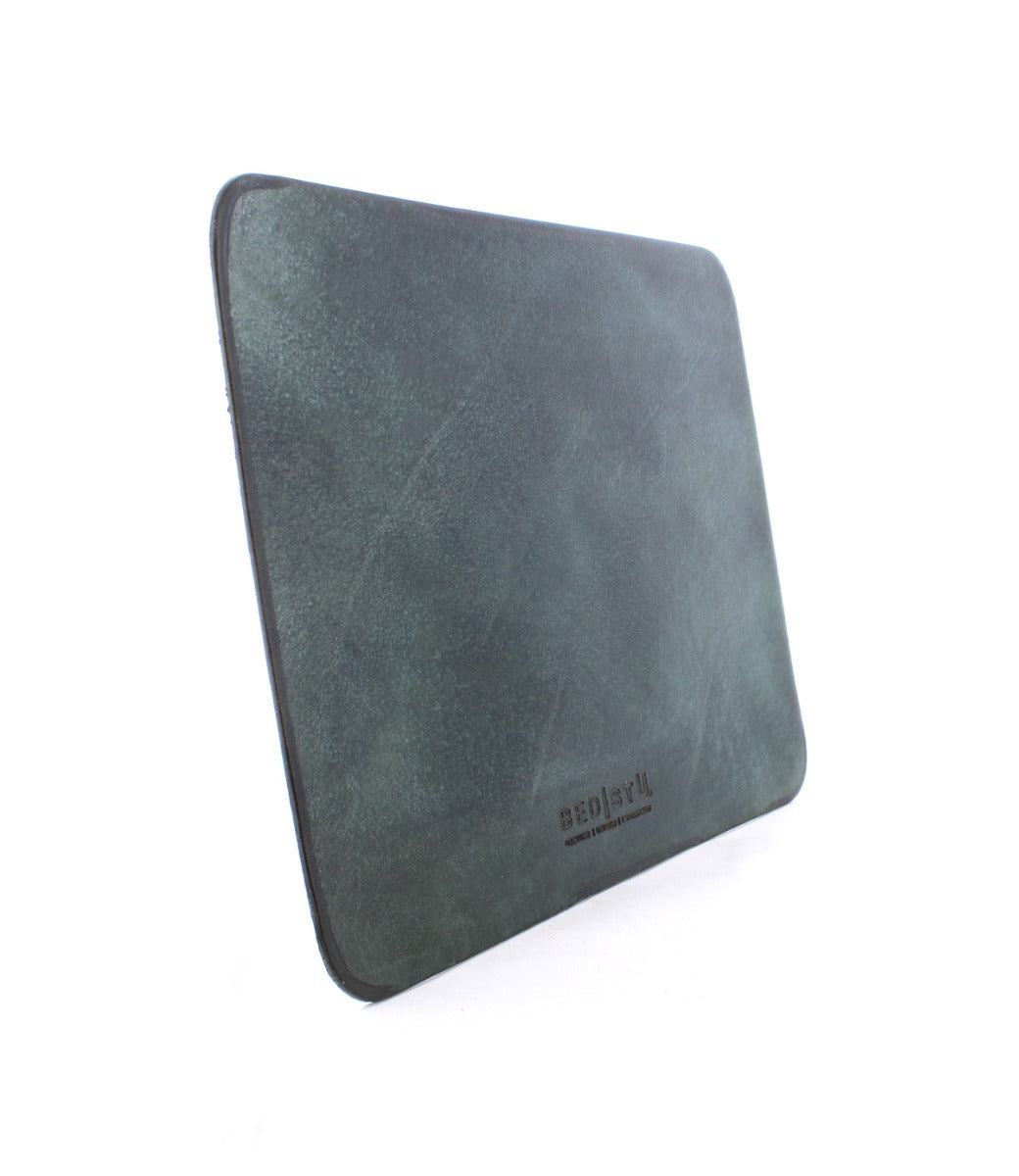 A dark green leather Launcher Mouse Pad with the brand name "Bed Stu" embossed on the lower front section, standing upright on a white background. The mouse pad features a suede underside for added elegance, perfect for a curated workspace.