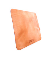 A rectangular leather Launcher Mouse Pad by Bed Stu in light brown color with a smooth texture, stitched edges, and a suede underside. The mouse pad displays a small embossed logo at the bottom center, perfect for a curated workspace.