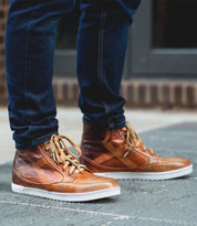 A man wearing a pair of Bed Stu Lordmind brown leather sneakers.