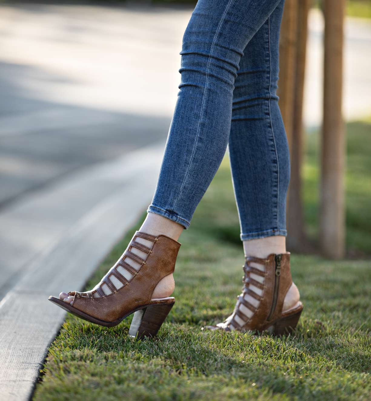 A woman wearing jeans and a pair of Bed Stu Occam P high heeled sandals.