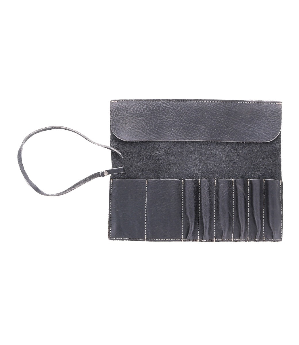 An open black leather Prepped Leather Wrap from Bed Stu, featuring multiple compartments and an attached strap, designed to hold small tools, artist tools, or accessories.