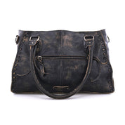The Bed Stu Rockababy black leather handbag, ideal for daily use, exhibits some noticeable wear. It comes with a front zipper pocket, two handles, and decorative stitching along the edges.