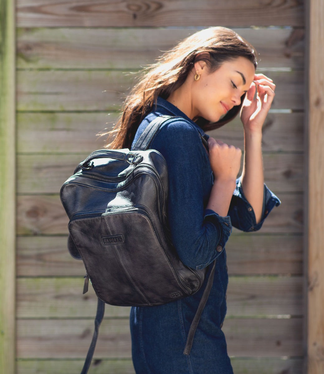 A woman wearing a black leather Bed Stu Rozes backpack.
