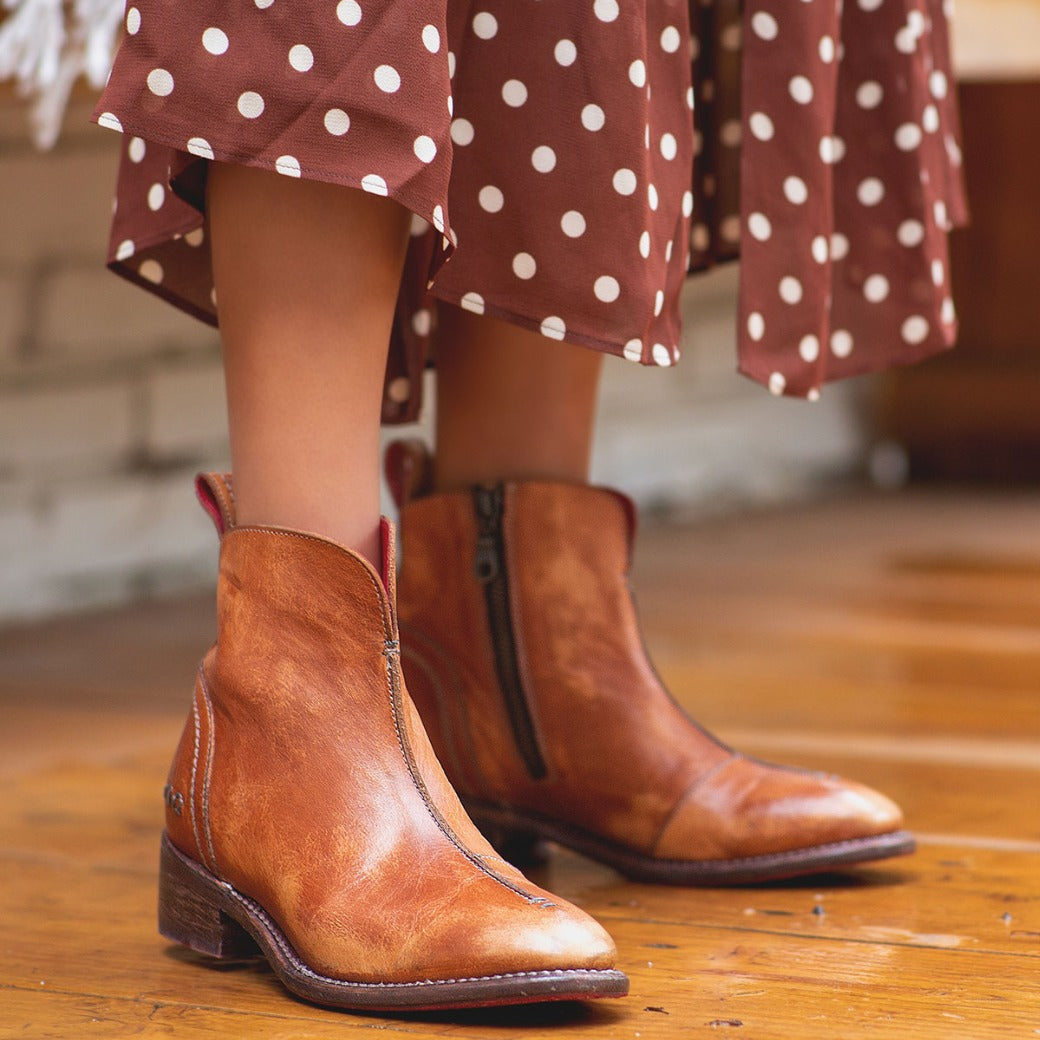 A woman wearing a Tabitha polka dot dress and Bed Stu brown leather ankle boots.