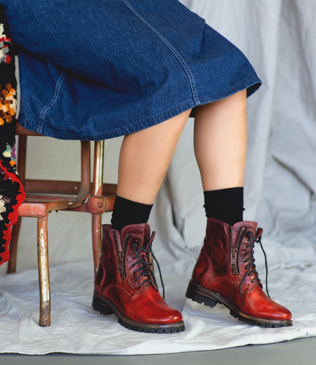 A woman is sitting on a chair wearing Bed Stu red boots.