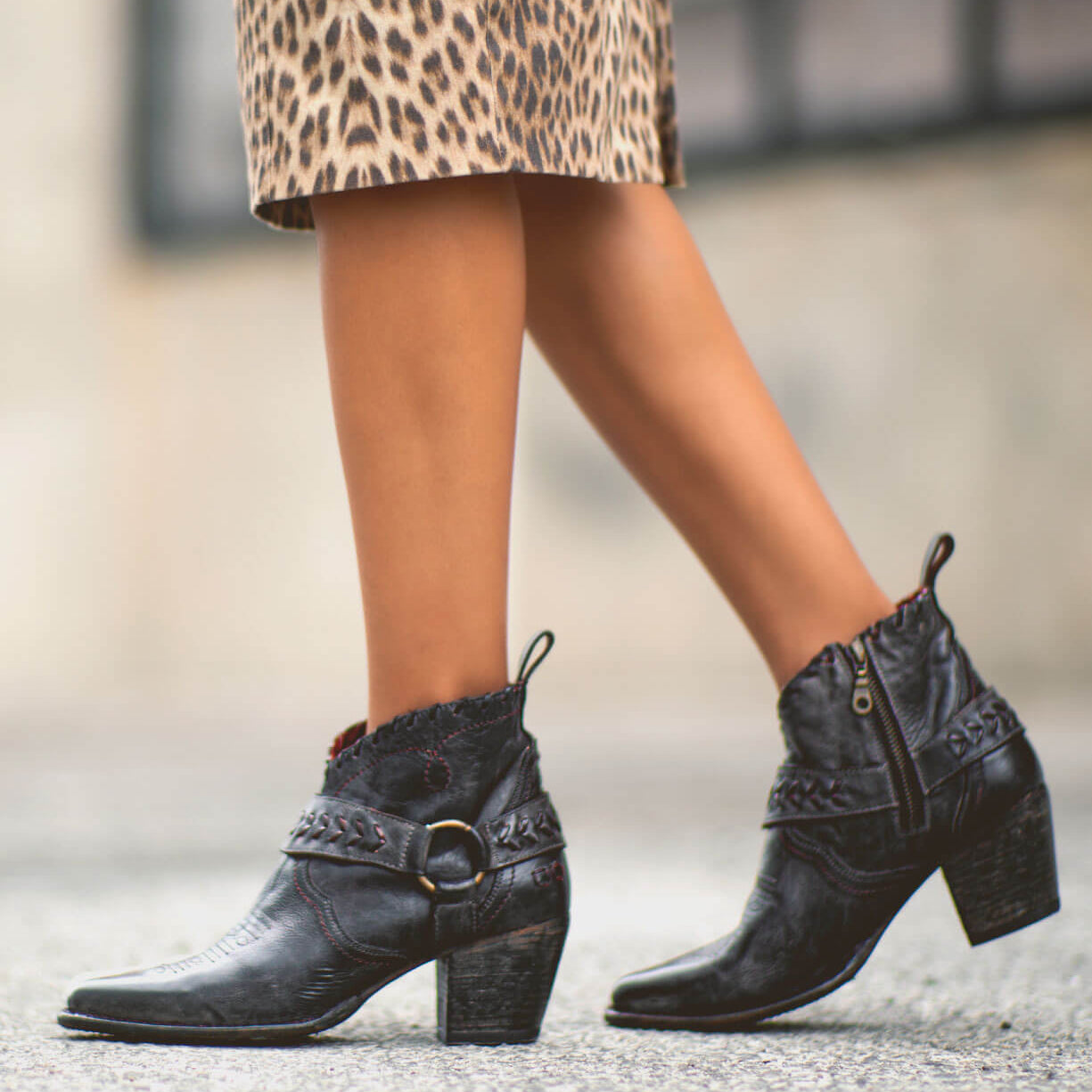 A woman wearing a leopard Tania skirt and black Bed Stu ankle boots.