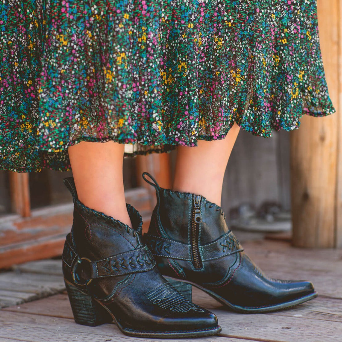 A woman wearing black Bed Stu cowboy boots and a floral skirt named Tania.