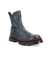 The Bed Stu Tanto is a single rugged men's boot in blue leather with studded side details and a thick brown lug outsole, shown on a white background for European-inspired style.