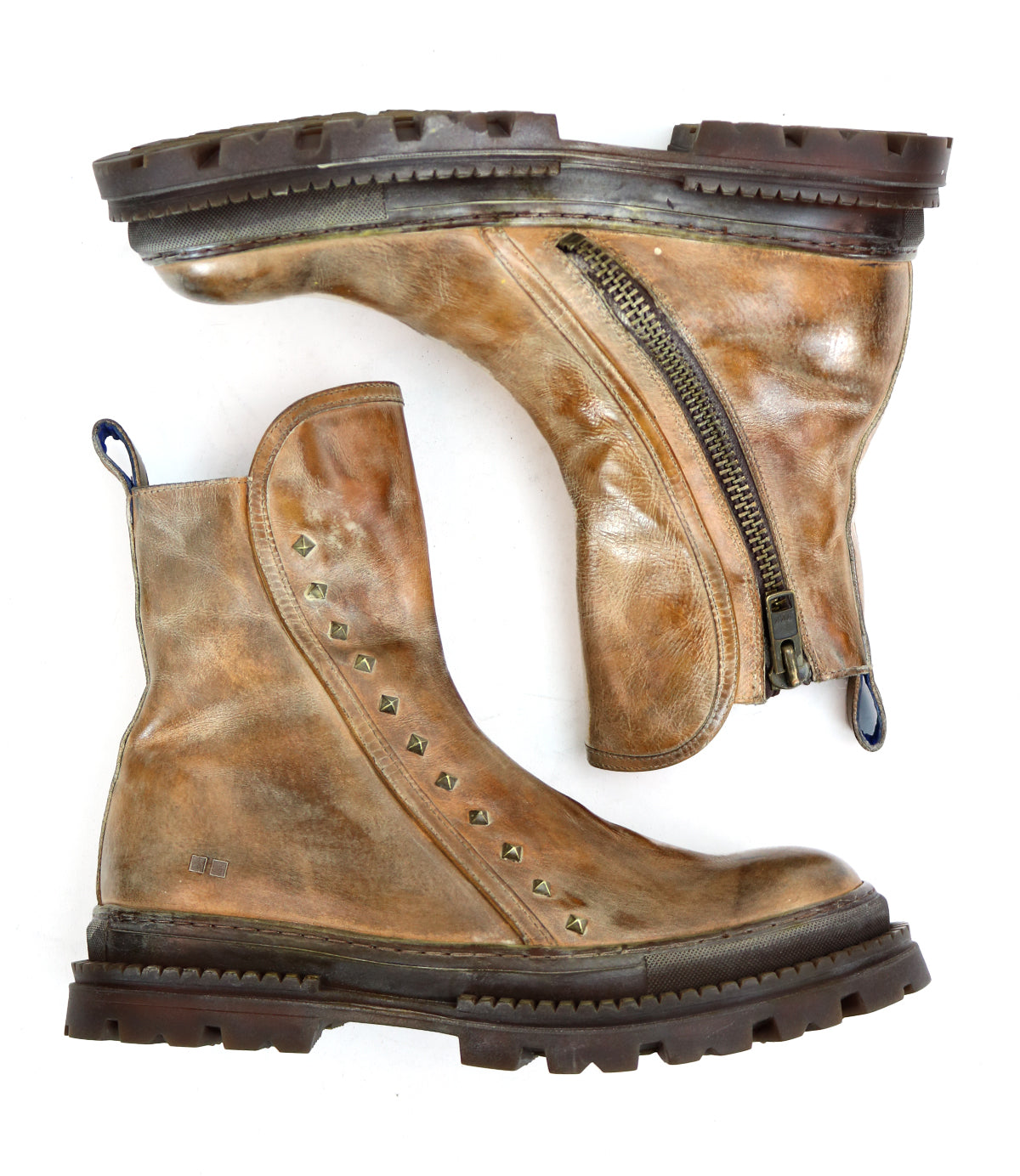 The Bed Stu Tanto boots are a pair of worn brown leather men's boots with side zippers, metal studs along the seam, and a rugged lug outsole, shown side by side on a white background for European flair.