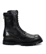 The Bed Stu Tempt is a black lace-up leather combat boot with a thick, rugged rubber sole, blending hiking boot durability and modern style, shown in side profile against a white background.