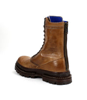 The Bed Stu Tempt is a brown leather lace-up hiking boot with a black lug outsole, side zipper, and blue inner lining, pictured from a rear side angle.