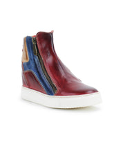 The Bed Stu Twist is a red high-top sneaker with blue and tan leather panels, a hidden wedge, side zipper, and white rubber sole, shown on a plain white background.