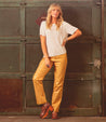 A woman is posing for a photo wearing Bed Stu luxury yellow leather pants.