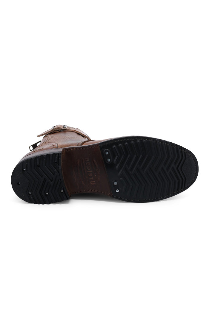A brown vegetable-tanned leather shoe with its sole facing upwards, showing black tread patterns and Bed Stu logo.
