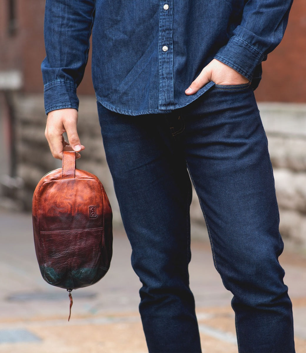 A man in jeans holding a Bed Stu Yatra leather bag.