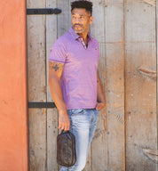 A man in a Yatra polo shirt leaning against a wooden wall. (Brand: Bed Stu)