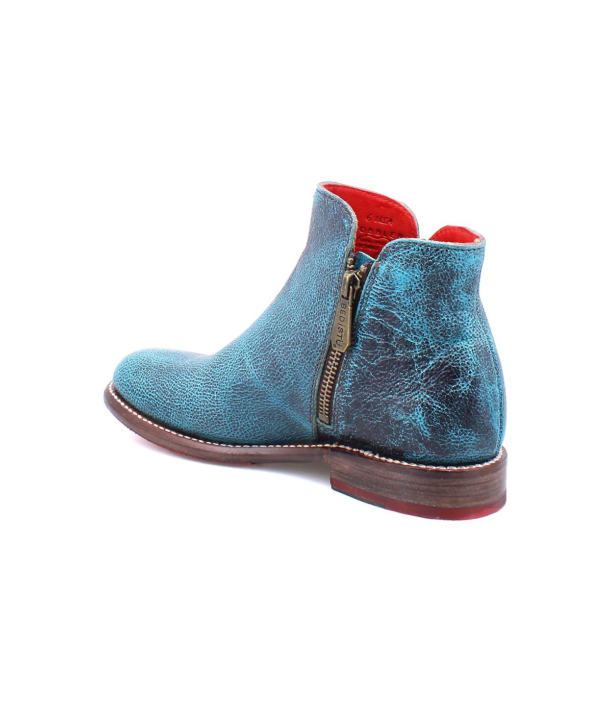 The Yurisa by Bed Stu is a timeless turquoise leather ankle boot with a textured finish, featuring a side zipper and a wooden sole. The interior lining is red, making it perfect for everyday wear.