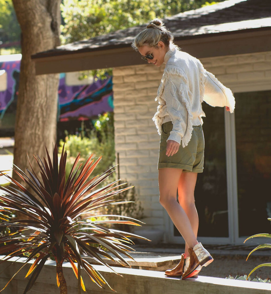 A woman standing on a ledge wearing Yurisa leather boots from the Bed Stu brand.