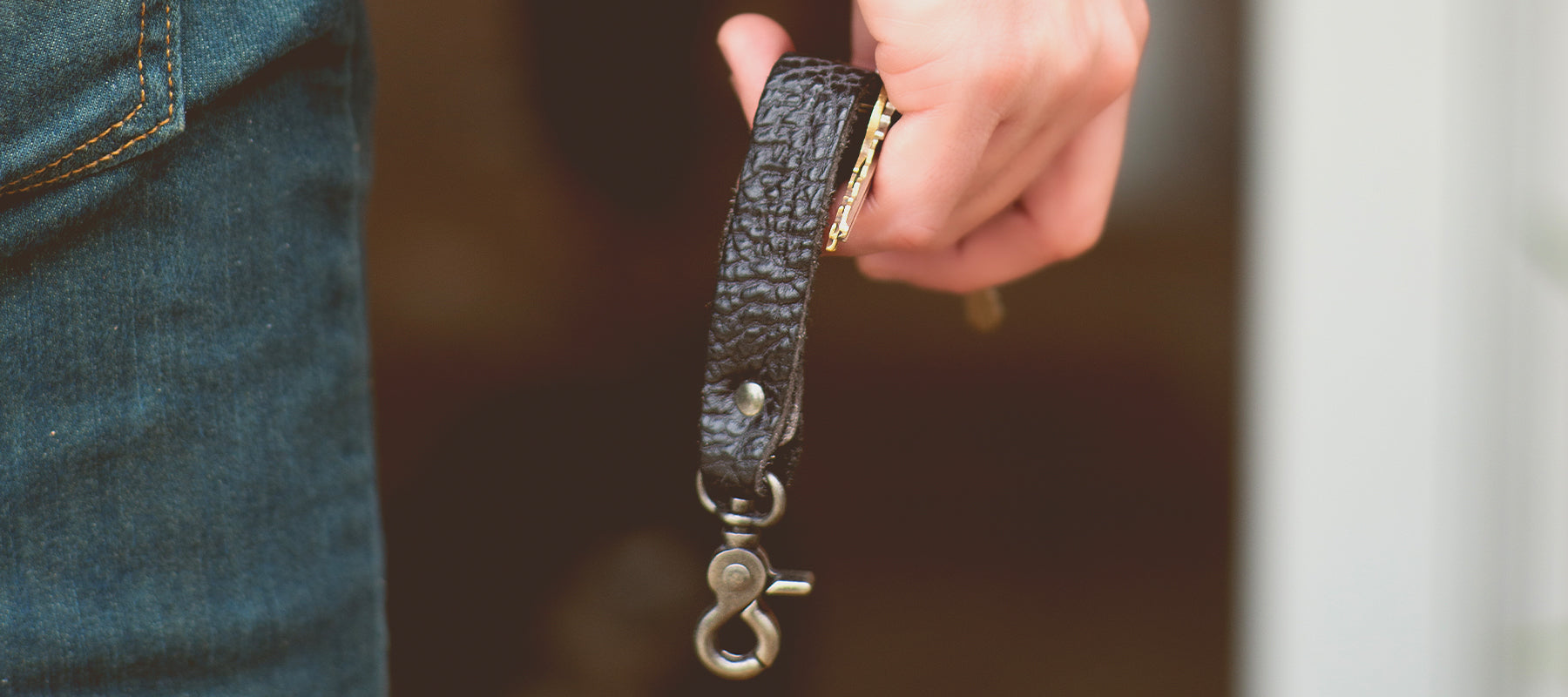 Close up on hand holding black leather keychian.