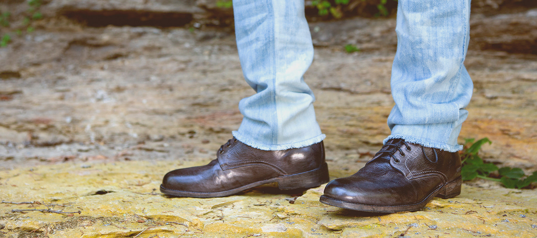 Close up of black dress shoes standing on rock ledge.