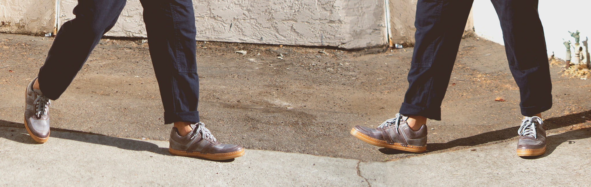 Man wearing tan boots with blue jeans walking in front of garage door.