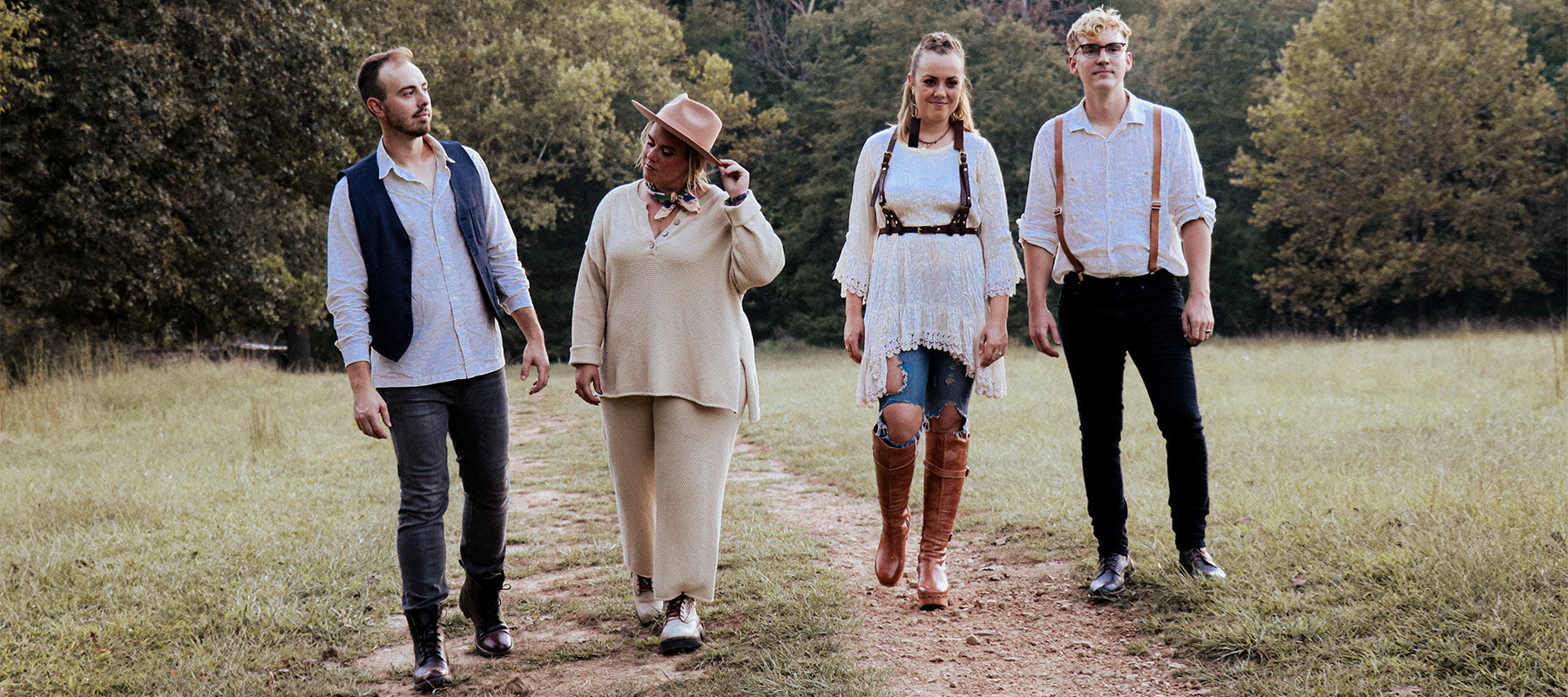 Four people standing on a dirt path in a field.