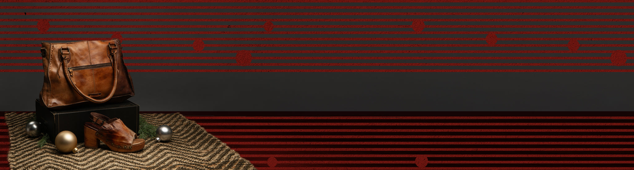 A brown leather handbag and shoes are displayed on a textured rug with metallic spheres and a striped background.