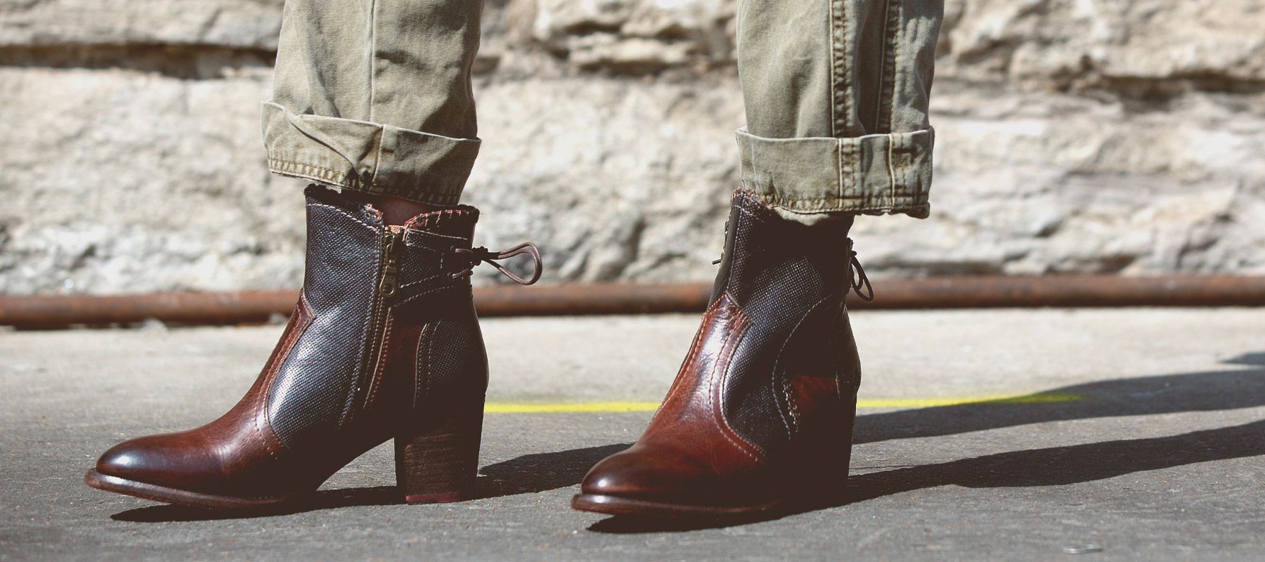 A girl standing in a concrete warehouse wearing a red bandana print long dress and brown leather Bedstu boots. 