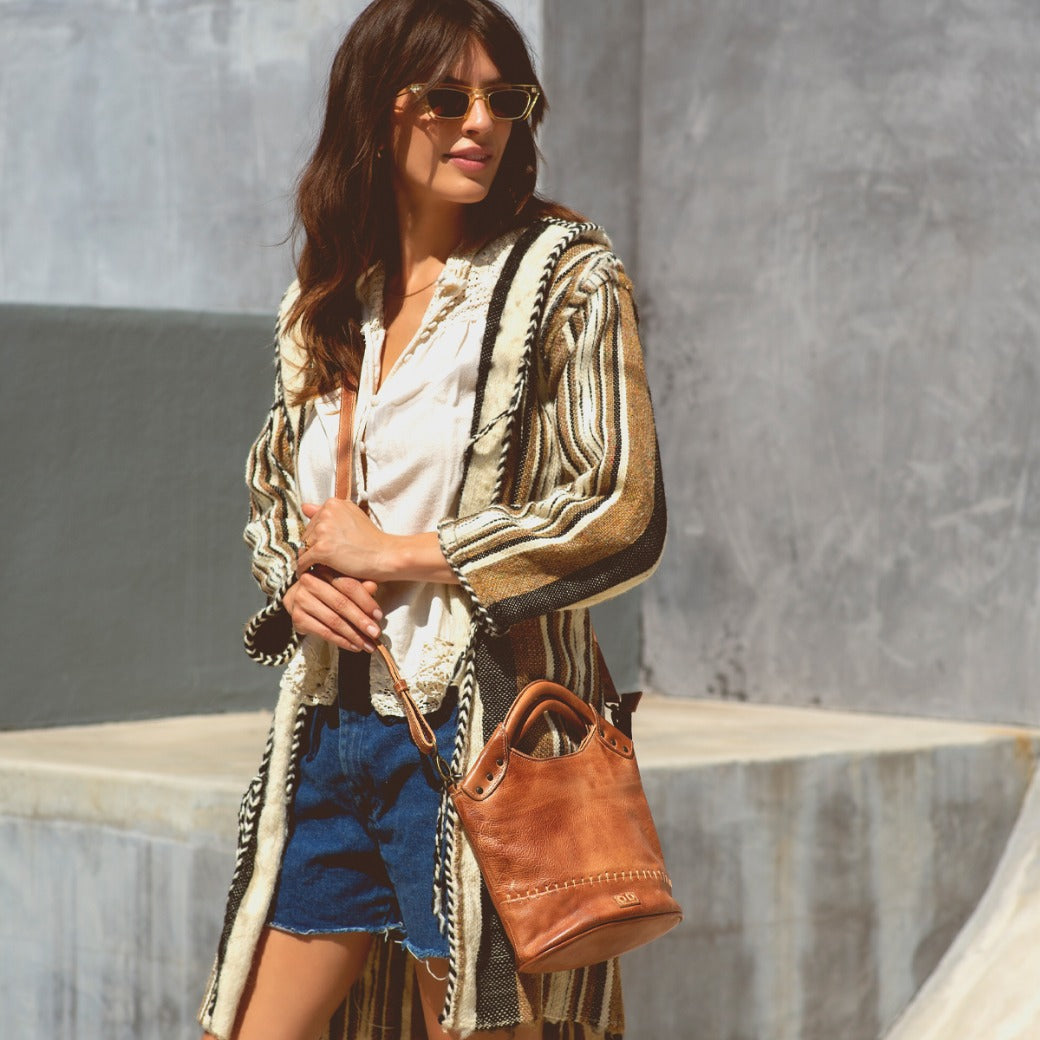A woman wearing a Delilah striped cardigan and Bed Stu denim shorts.