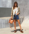 A woman in Delilah denim shorts and a striped Bed Stu jacket standing on a skateboard.
