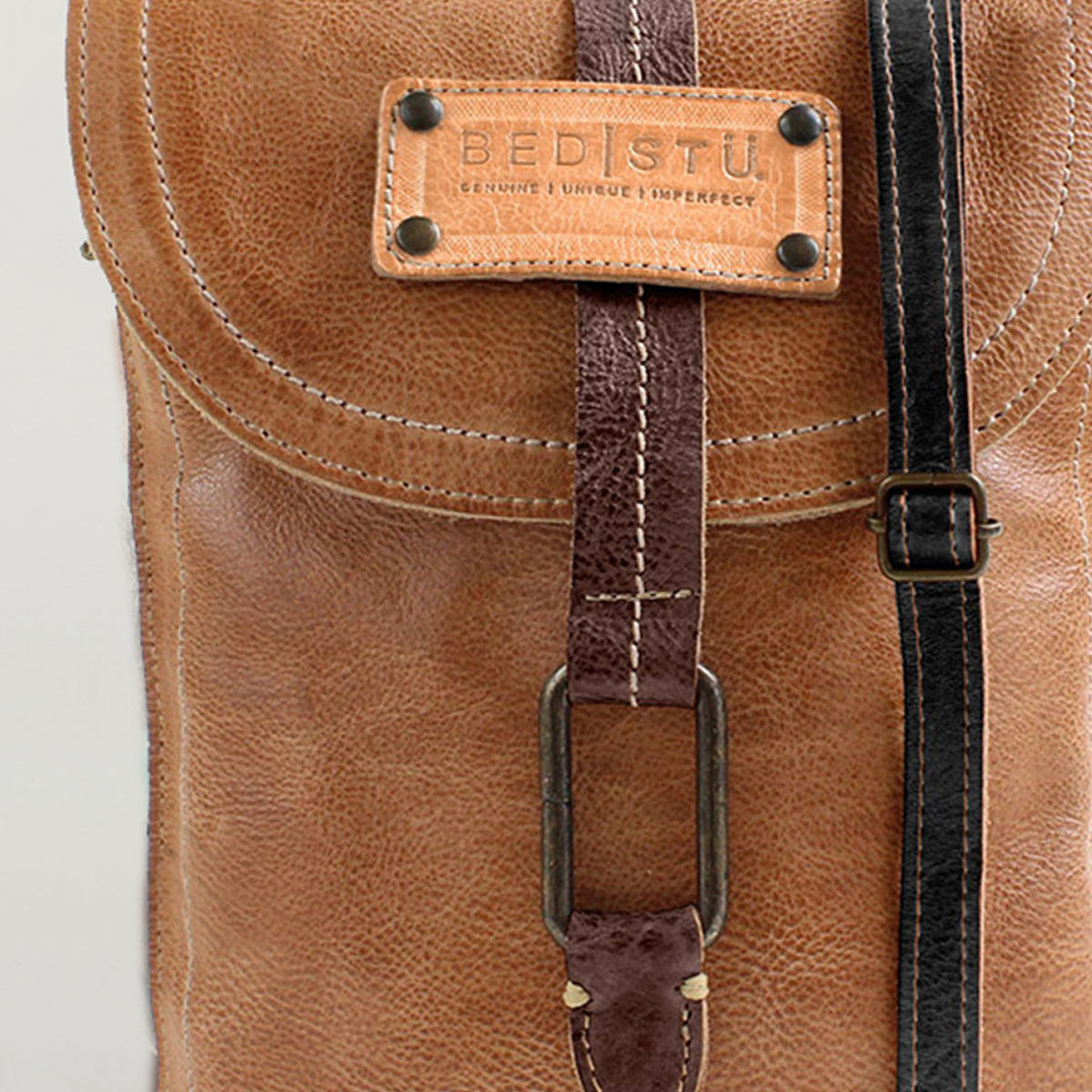 Close-up of a brown leather Bed Stu Studio Ring Strap backpack featuring a front buckle strap and stitching details, showcasing the creativity that goes into crafting such a personalized bag.