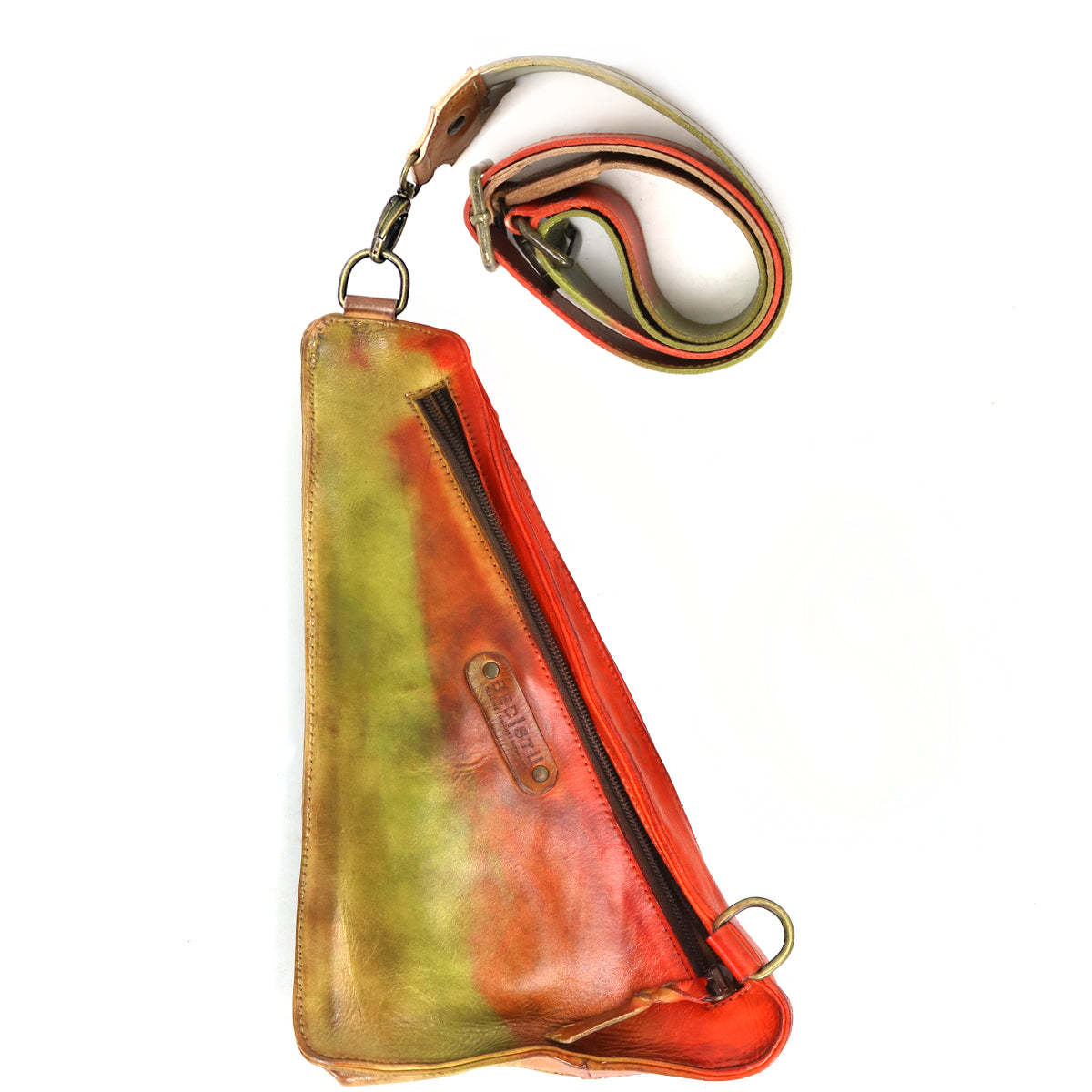 The Adept by Bed Stu is a triangular-shaped sling bag crafted from sustainable leather, featuring multi-colored hues of vibrant red, green, and brown. It includes a zipper and an adjustable strap.