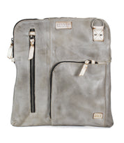 The Bed Stu Aiken is a square gray leather convertible crossbody bag featuring two front zippered pockets, a metal ring accent, stitched brand labels, and an adjustable strap for versatile styling.