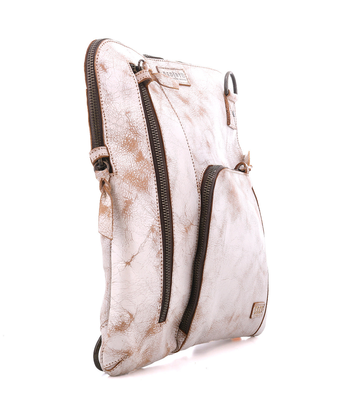 The Bed Stu Aiken is a slim, light beige convertible crossbody with an adjustable strap, textured finish, two front zippered pockets, and dark brown zipper accents, shown upright against a white background.