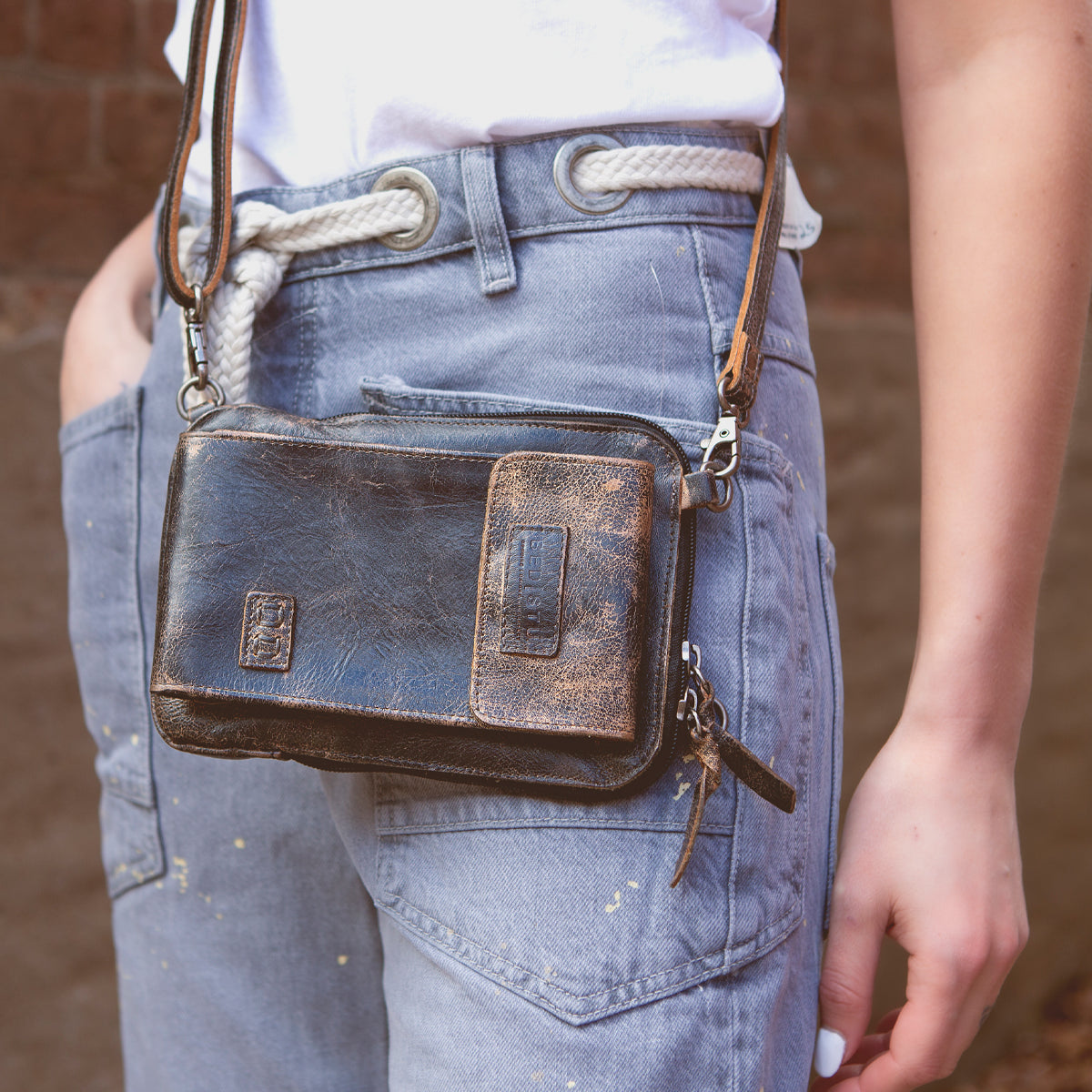 A woman wearing jeans and a Bed Stu Alelike premium leather crossbody bag.